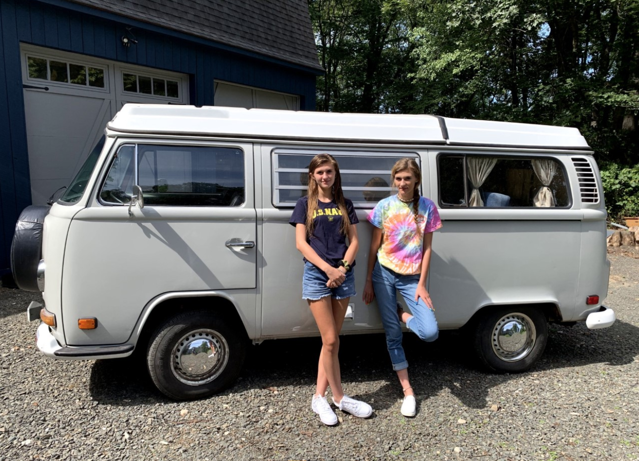 Young changemakers Allie and Chloe in front of a van that they converted to electric engine. 
