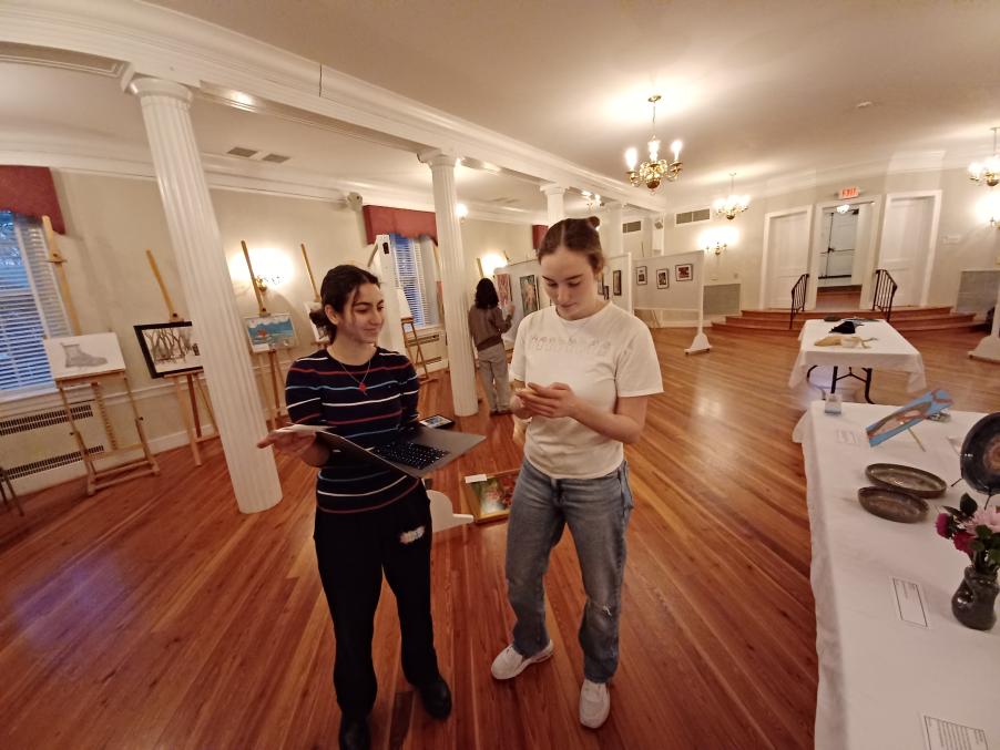 50/50 Club treasurer Alice Merolli and president Alexandra Himmel plan how to arrange the art the night before the show (photo courtesy of Margaret Gammie)