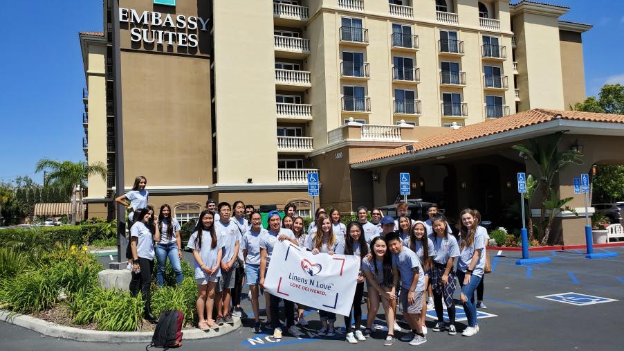 A group of Linens N Love volunteers stand in front of an Embassy Suites.